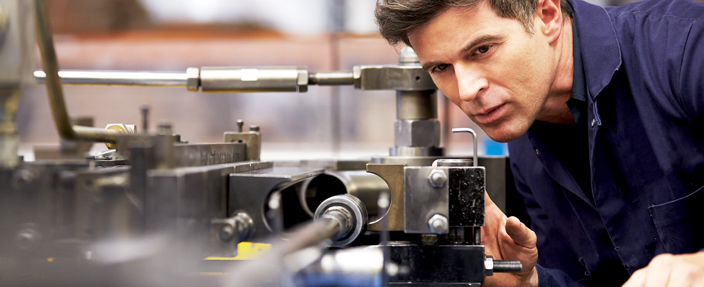 en man tittar fokuserat på en del i en industrimaskin